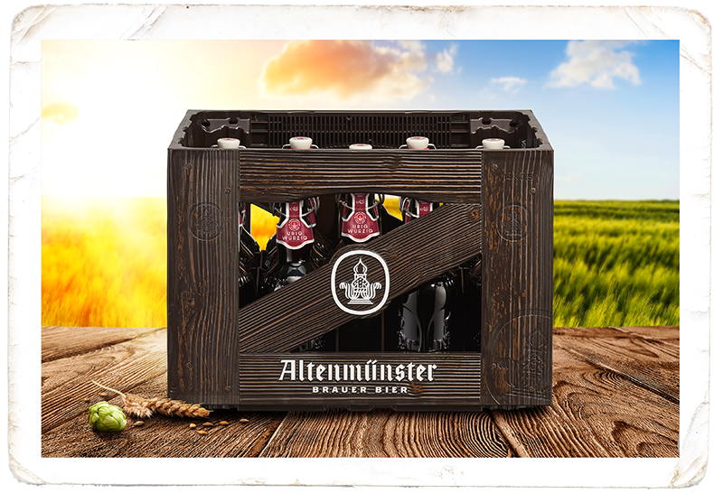 Ein Holzkasten mit dunklen Bierflaschen steht auf einem Tisch vor einem Weizenfeld.